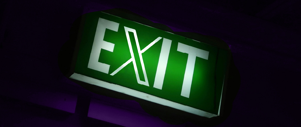 Green EXIT sign on the dark background 